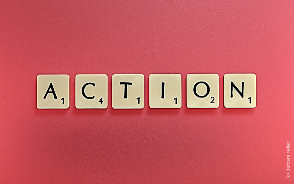 Scrabble Buchstaben bilden das Wort "Action" auf rosa Hintergrund