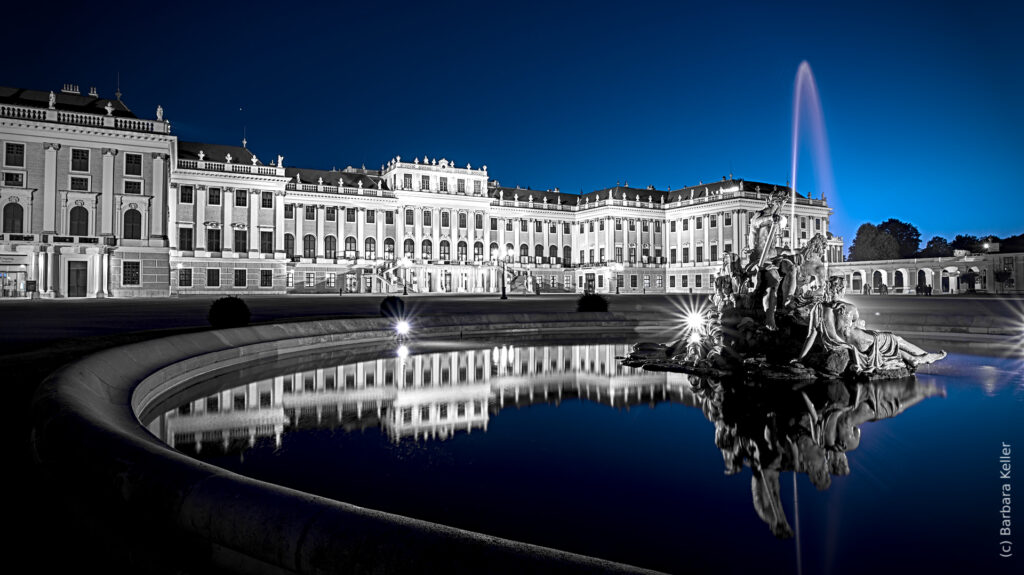 Schloß Schönbrunn in Wien zur blauen Stunde mit Spiegelung im Wasser eines Springbrunnens: Nachtaufnahme