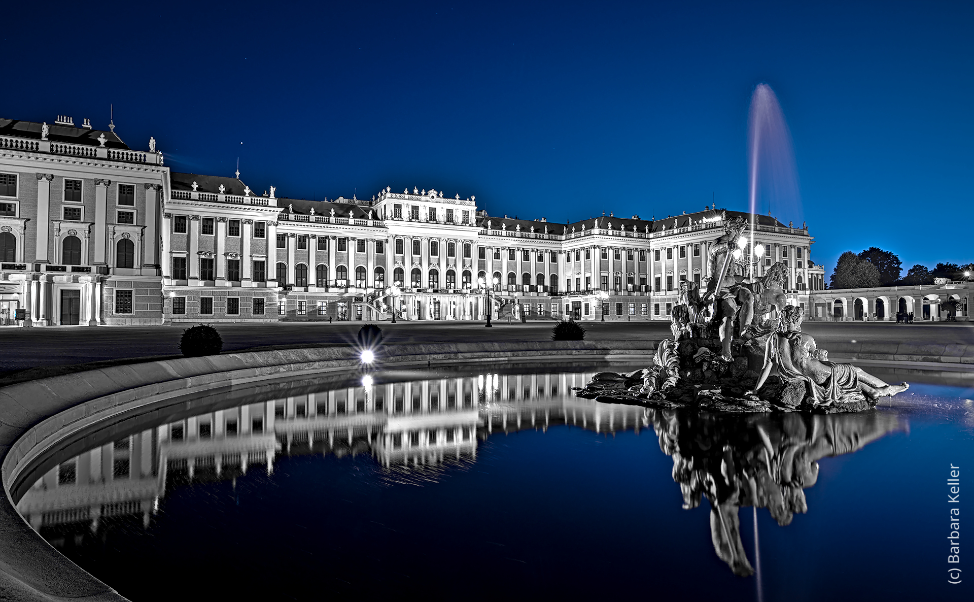 Schloß Schönbrunn in Wien zur blauen Stunde mit Spiegelung im Wasser eines Springbrunnens: Nachtaufnahme